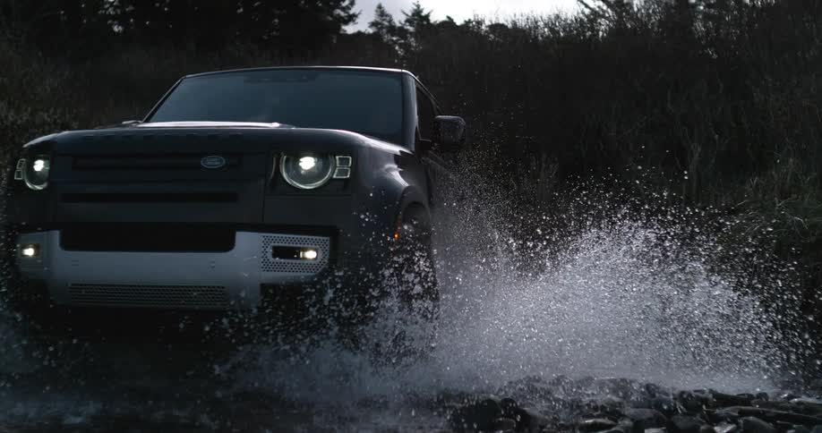 Black suv car driving along river splashing water