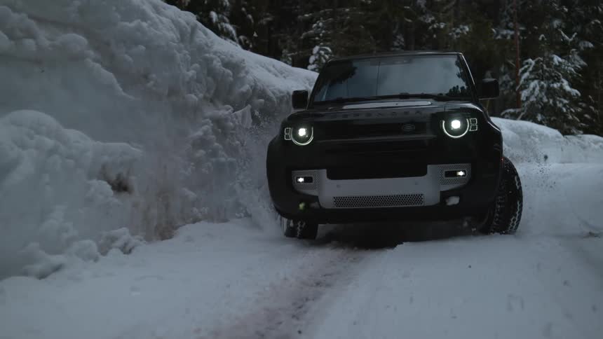 An suv drifts over a snowy road in a forest struggling to regain control