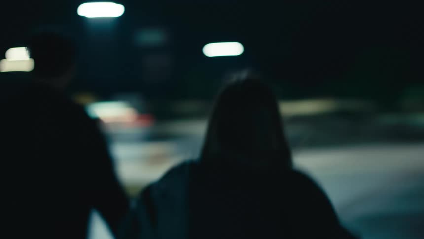 Woman and man walk hand in hand down the street at night