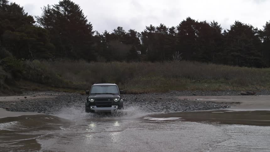 A sport utility vehicle drives into the water