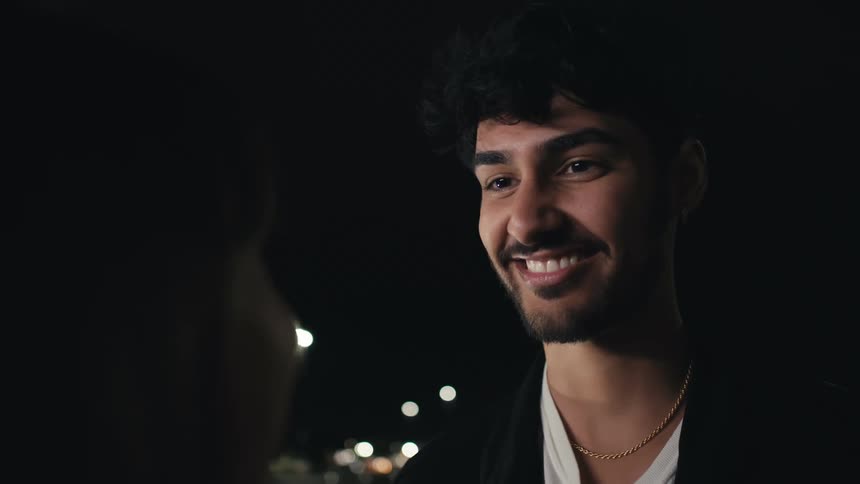 Man with beard and woman look into each others eyes smilingly at night