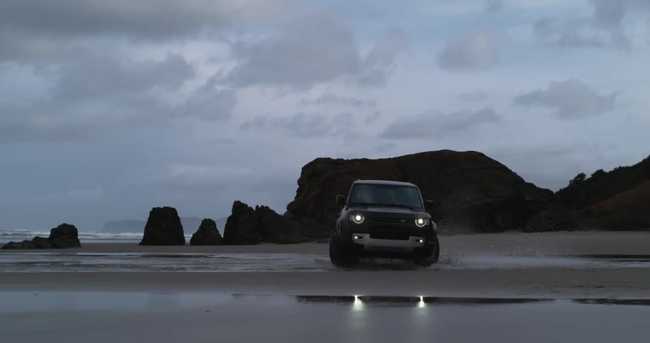 Black suv car drives on the beach on cloudy day