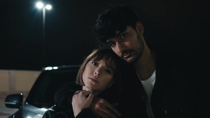 A couple pose on the hood of their car