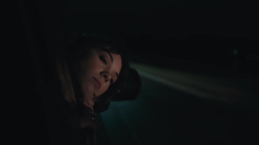 Woman with dark hair sticks her head out of car window at night