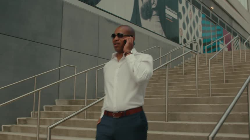 A man is walking down a staircase and talking on a cellphone