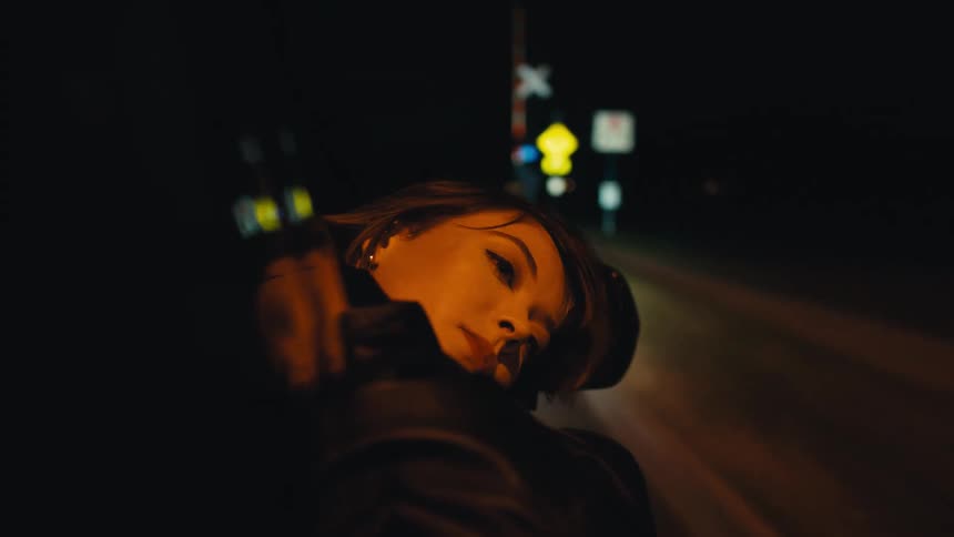 Woman sticks head out of car driving on highway at night