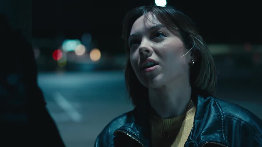 Man and woman speak while standing in the middle of the road