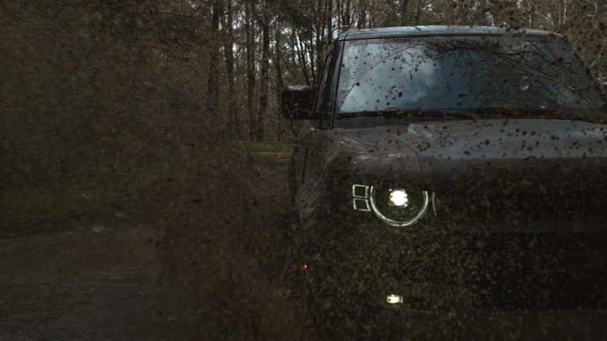 A sport utility vehicle drive down a muddy trail in the woods