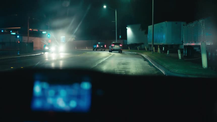 Vehicles drive down a wet highway at night