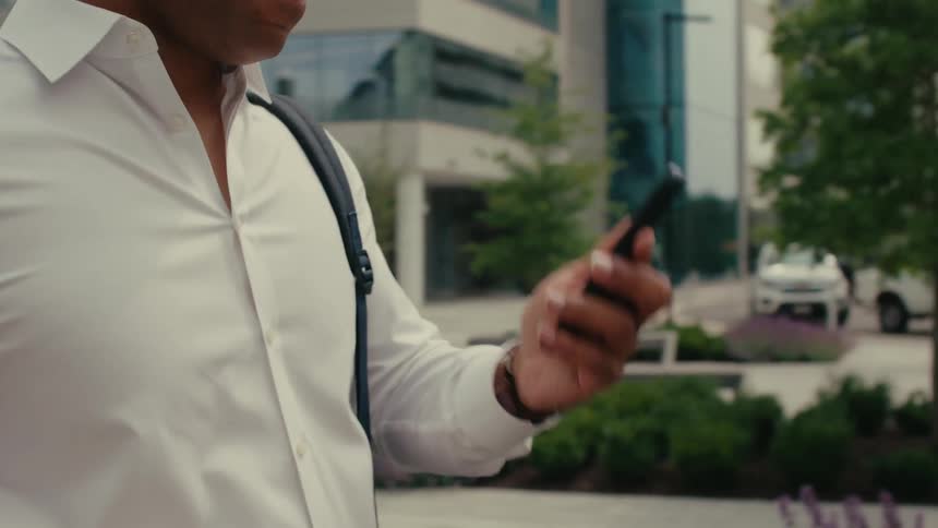 A smiling man interrupts a phone call to check his phones screen and then continues