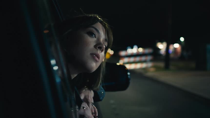 A woman sticks her head out of a car window