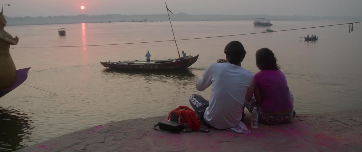 Two people watch the boat travel away