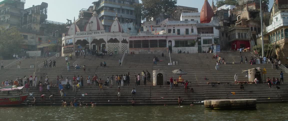 Several people stand on steps leading to waterfront near docked boat and concrete platform set in water
