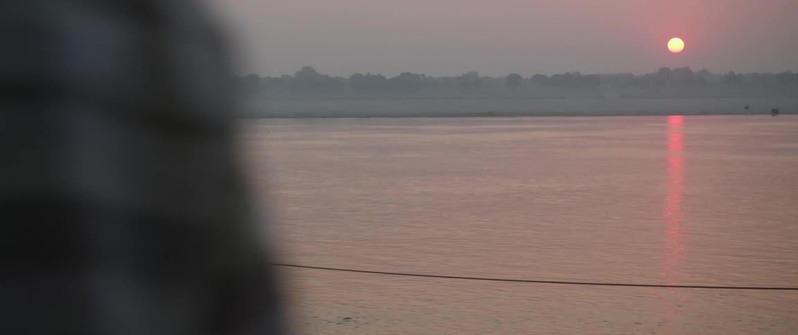 A small barge with two people approaches a pier with an indian statue