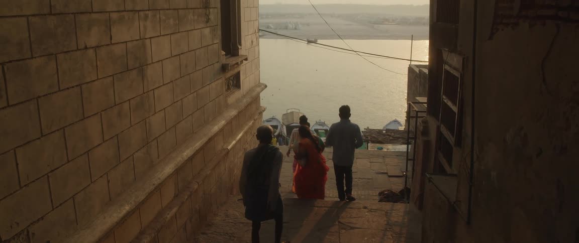 Indian people walk down the narrow street to the coast at sunrise