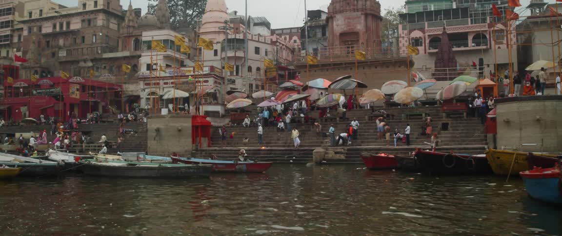 People stand on steps under umbrellas along the coast