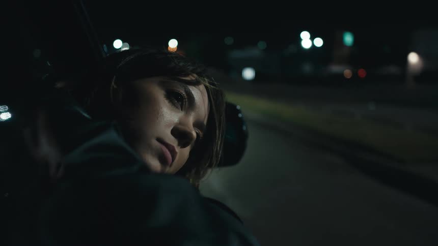 A sad woman has her head out a passengers car window