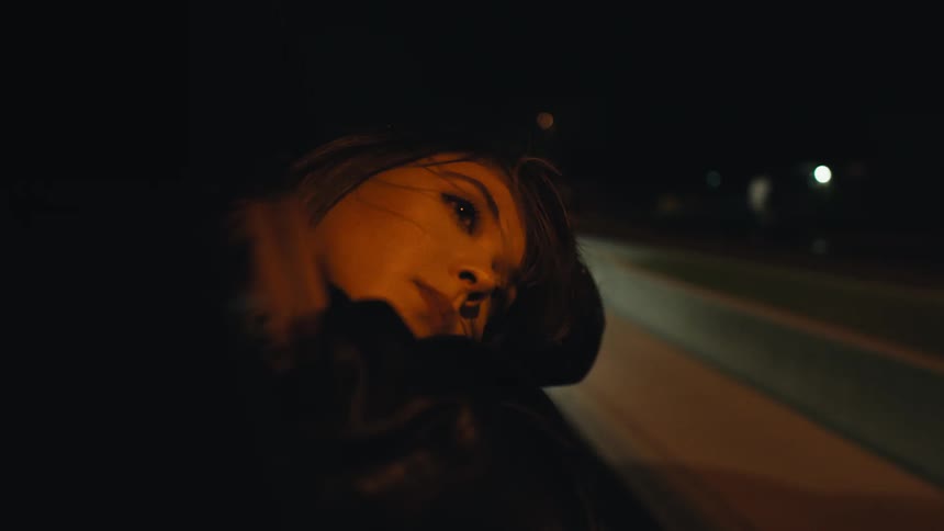 A woman rest her head on a car window while riding as a passenger