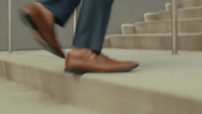 Man with blue suit and brown leather shoes climbs stairs