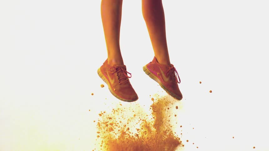 A woman jumps through yellow colored powder