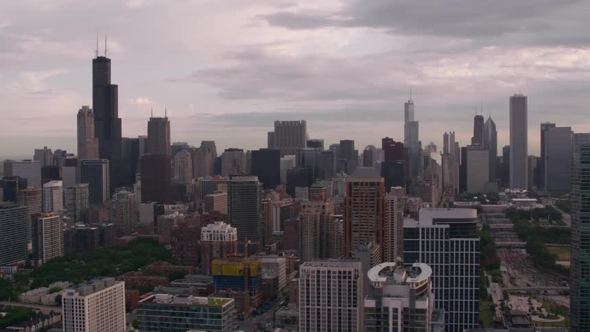Towers and skyscrapers overlook the city as traffic moves on the streets under a cloudy sky