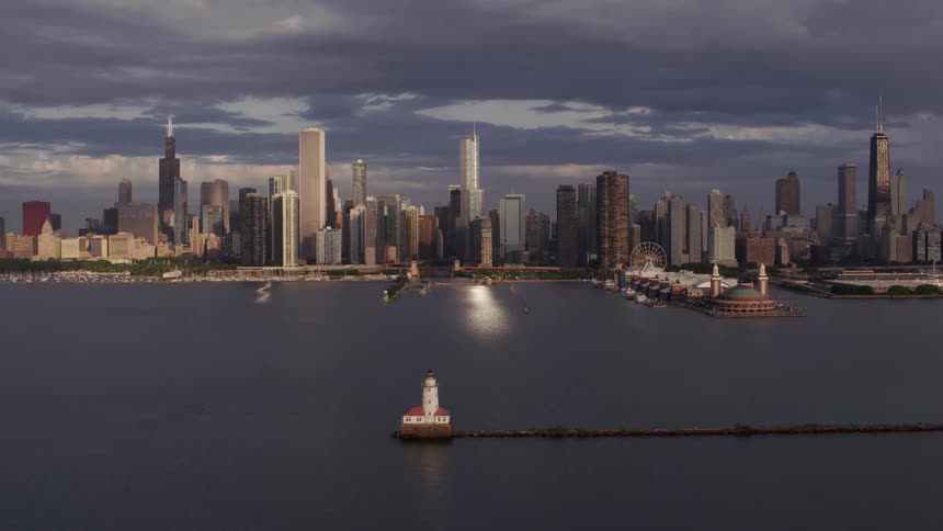 Towers and skyscrapers overlook boats sailing in the water near the metropolitan city on the coast under a cloudy sky