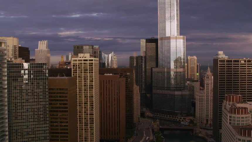 River winds through city past skyscrapers and cranes under dark clouds