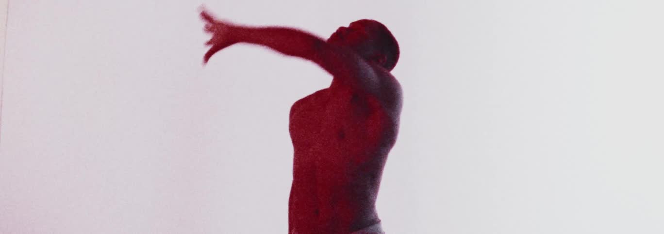 Topless man in red light dances in the studio