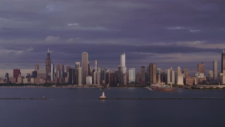A cityscape including a marina with several boats docked and an area of water marked by a buoy