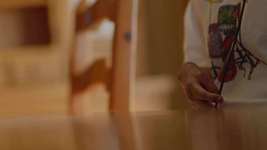 A man is standing next to a table as he pulls a thick black string