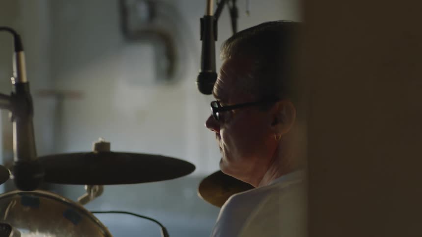 Disabled man with glasses and white t shirt plays drums