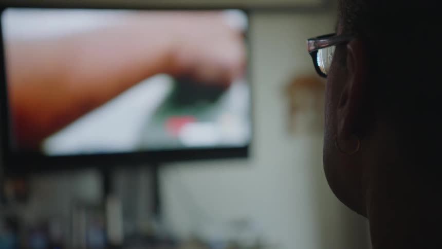 Disabled man with glasses watches televison