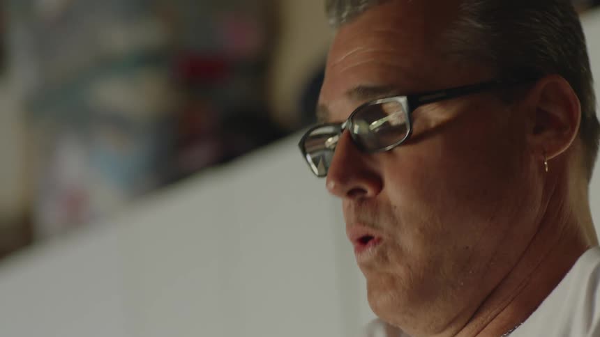 Man with glasses earrings and white t shirt breathes