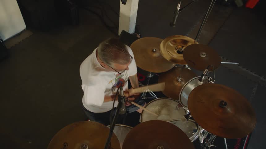 Disabled man with white t shirt and sunglasses plays drums