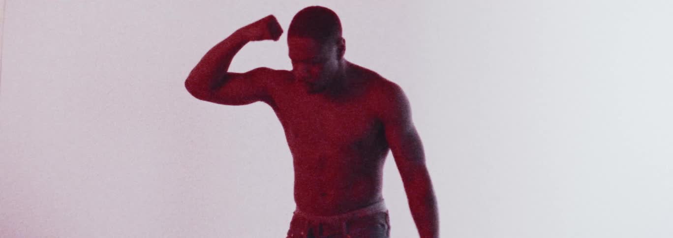 Shirtless man with earrings and jeans dances in red light in the studio