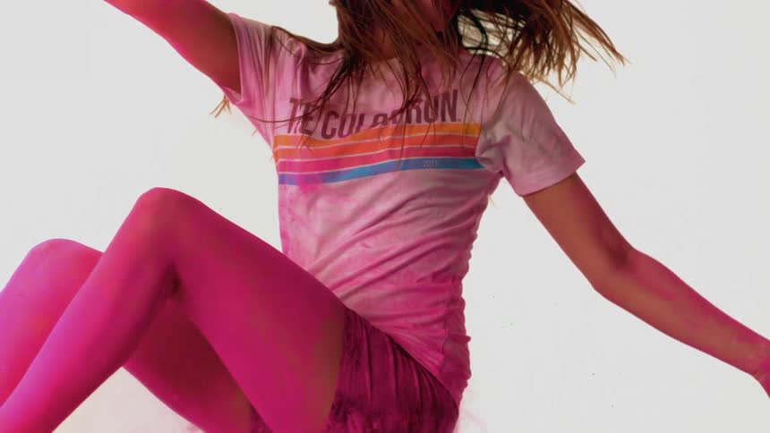 A young woman flies through the air surrounded by pink powder