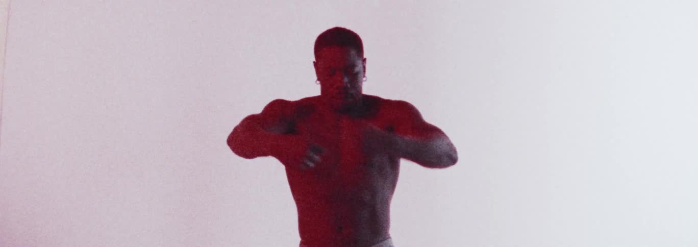 A man without a shirt on standing and moving or dancing around by himself