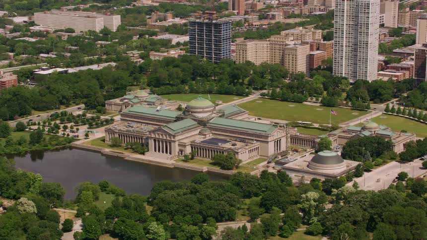 An aerial view of a city including a classical building with a domed center and a lake