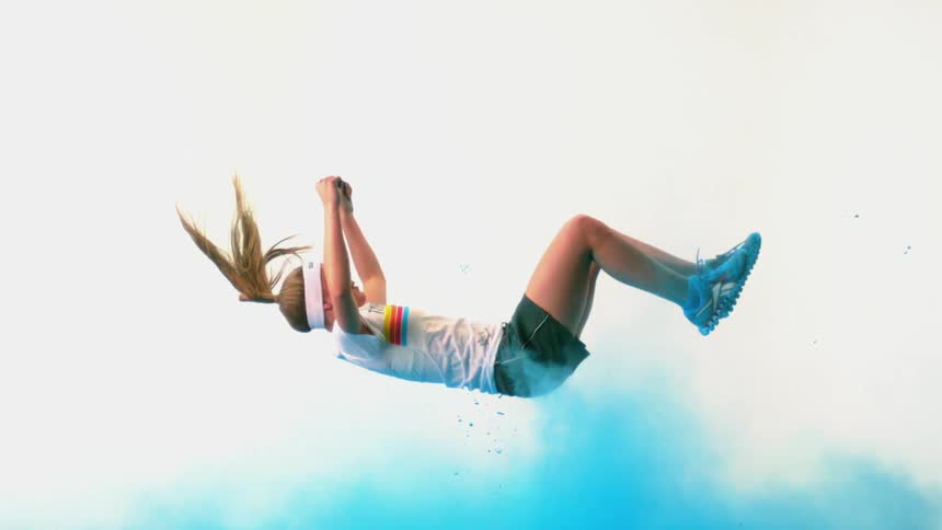 A girl falling through the air into a cloud of blue colored powder