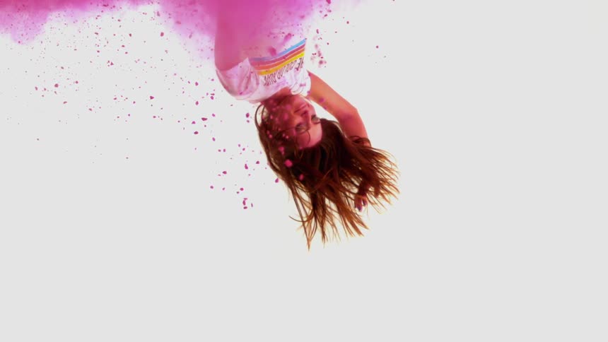 Young woman falling through a cloud of pink powder