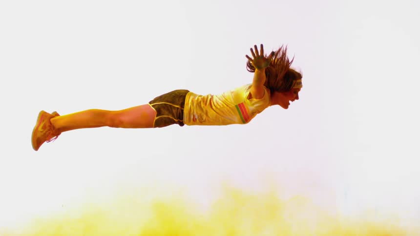 A woman is falling onto some yellow powder