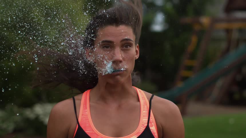 A woman is spitting out water in extreme slow motion