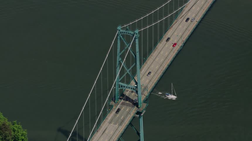 Cars drive along a bridge as a boat passes underneath