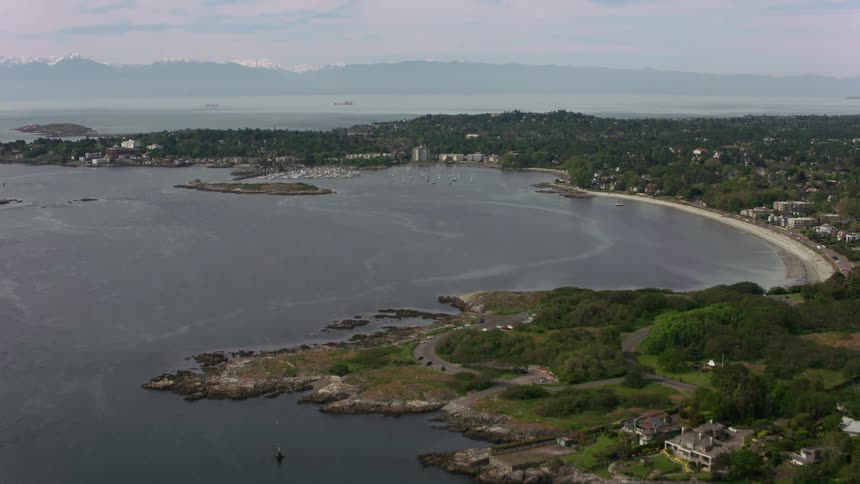 An aerial view of a coastal area including several small islands a beach scattered houses and a forest