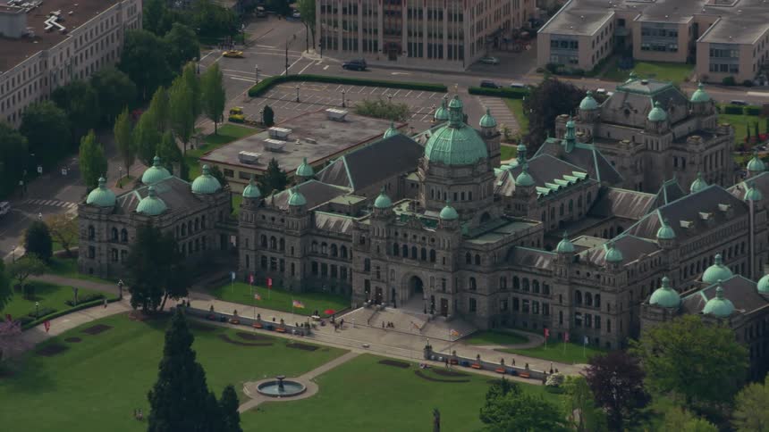 Traffic moves along street next to historic green domed government building with large lawn