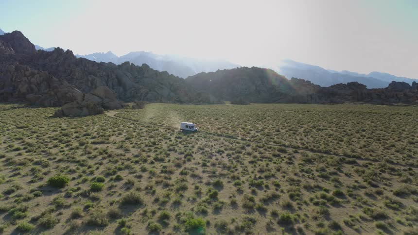 A delivery truck driving through a path on a grassy plain