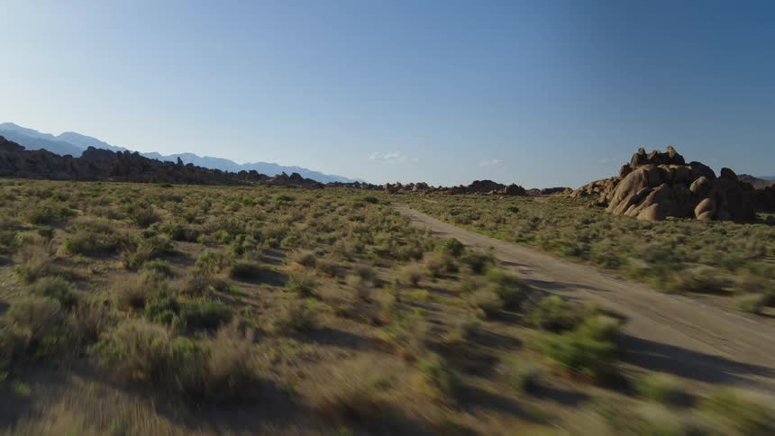A dirt road on a grassy plain with many rock formations