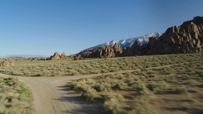 A dirt road crossing a grassy plain surrounded by rock formations