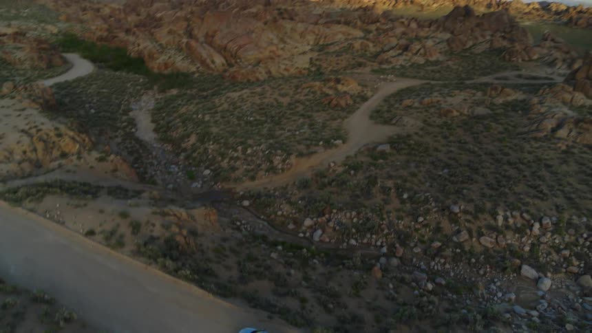 Aerial view of gray car driving on country road over the mountainous terrain