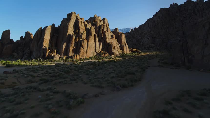 A dirt road crossing a grassy plain surrounded by rock formations